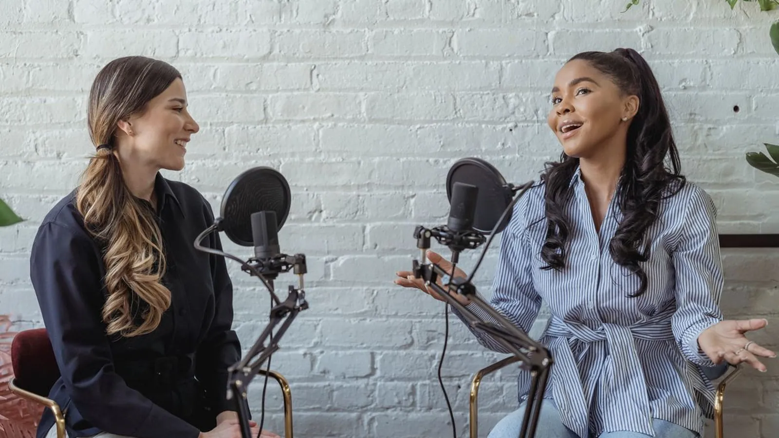 Two podcast hosts speaking into studio microphones during a recording