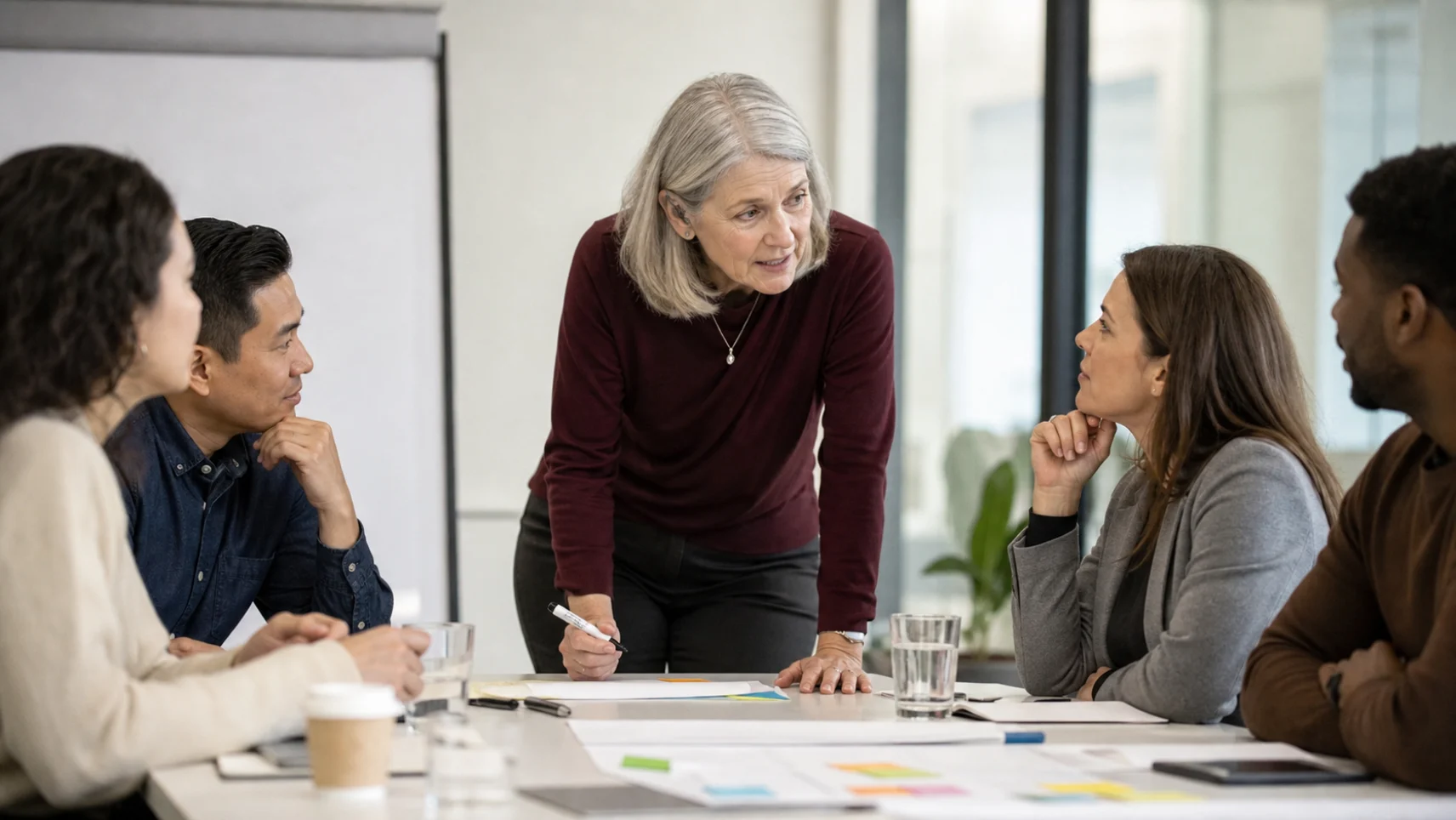 A workshop leader coaching a group of executives around a conference table during a storytelling session