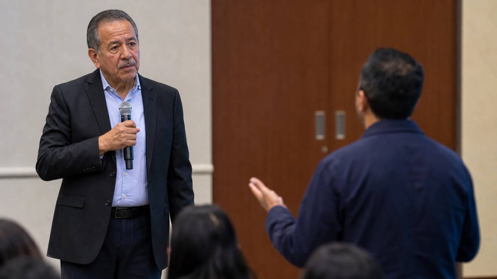 A speaker with a handheld microphone answering a question from someone standing in the audience