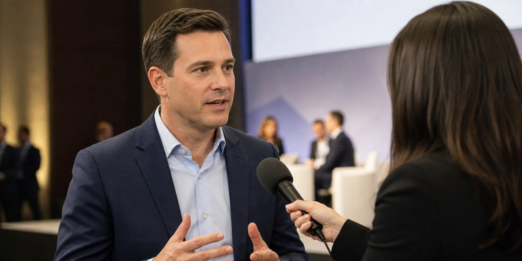 Man in business casual being interviewed with microphone at conference event.