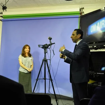 Jess Todtfeld filming a client in a mock interview in front of a studio backdrop